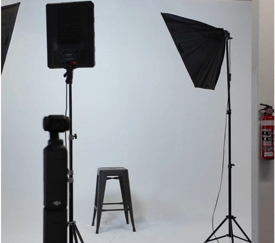 The studio set up for a shoot: softbox lights, a stool and a white backdrop.
